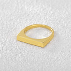 side view of gold plated geometric bar ring on white fabric