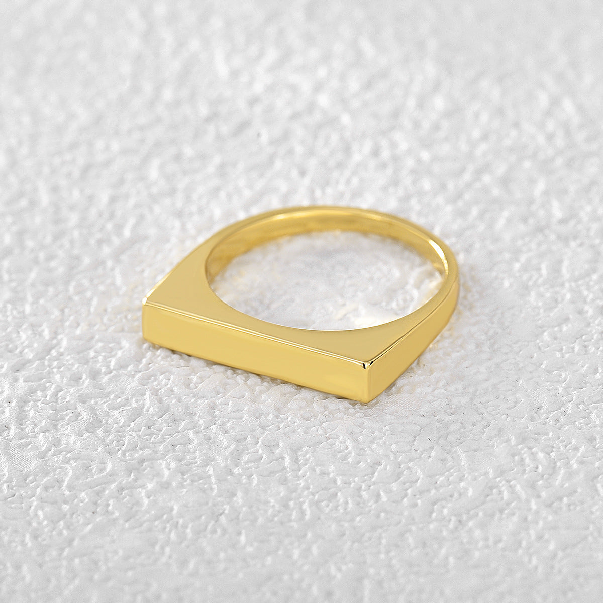 side view of gold plated geometric bar ring on white fabric