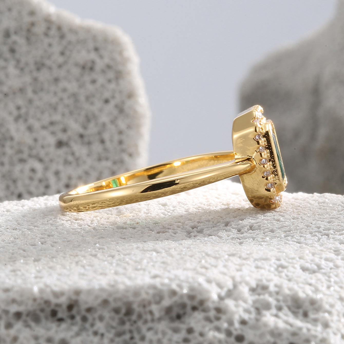 side profile of raised green zirconia halo setting on gold plated band