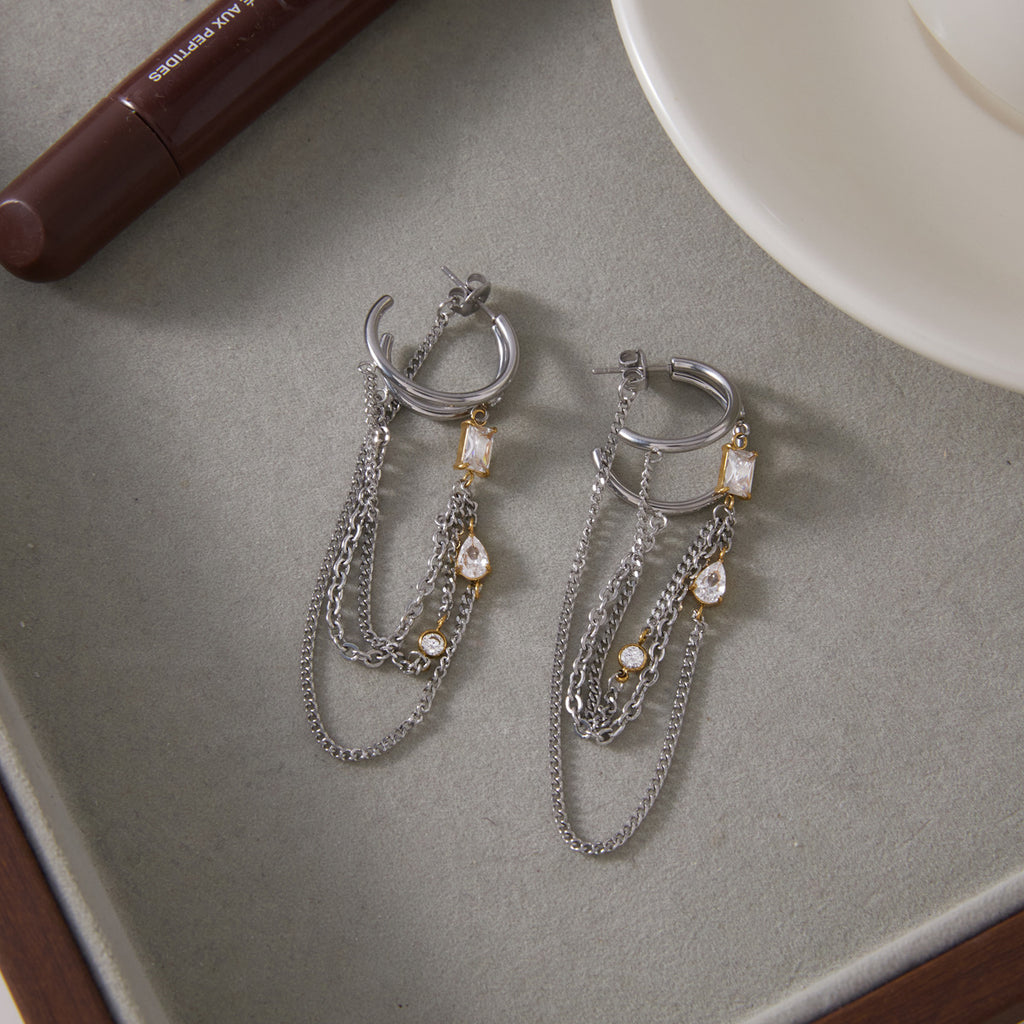 Pair of open hoop earrings with hanging chains on a tray