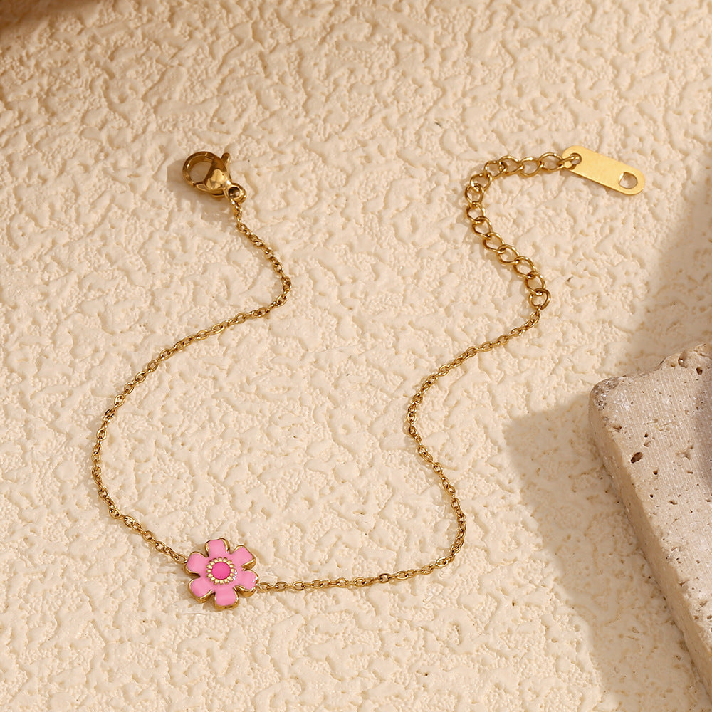 Fine-chain pink flower bracelet arranged beside a textured prop