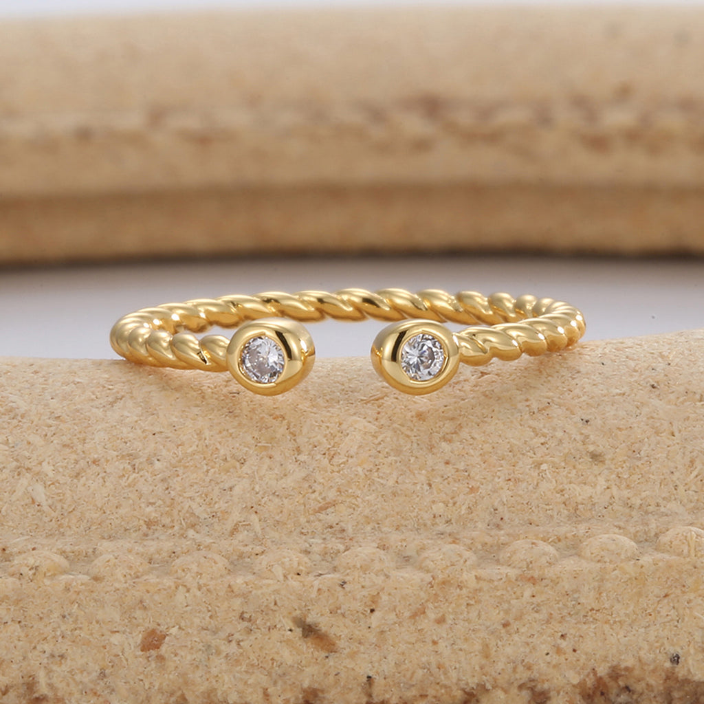 gold plated twisted zirconia open ring styled on a stone surface