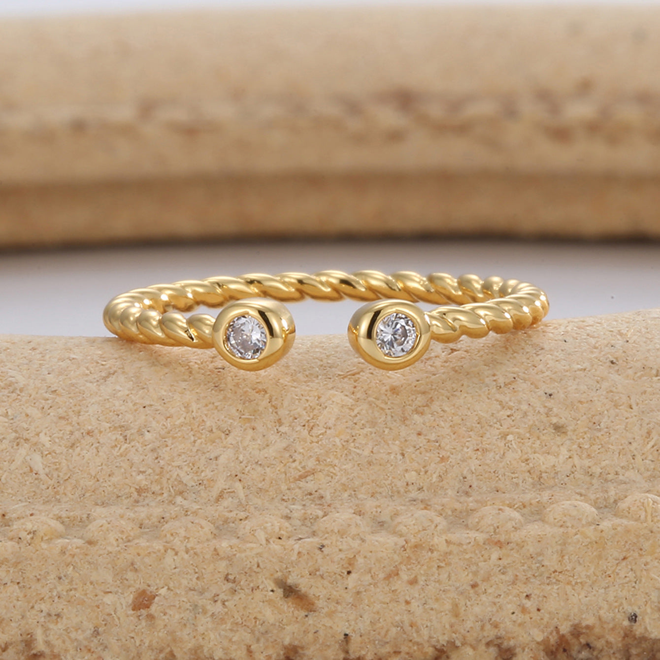 gold plated twisted zirconia open ring styled on a stone surface