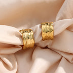 gold plated textured wide hoop earrings styled on cream fabric
