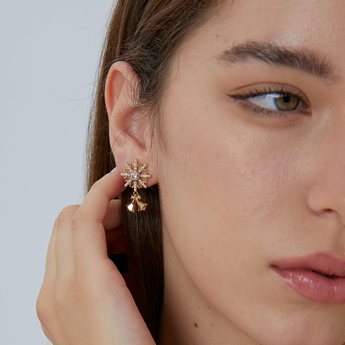 Snowflake and bell drop earrings shown worn on the ear
