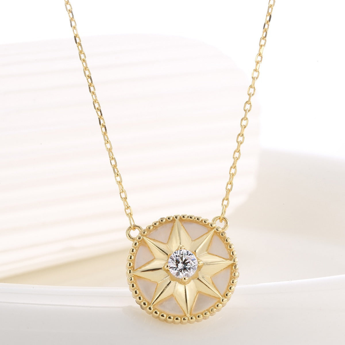 angled close view of eight-point compass star necklace