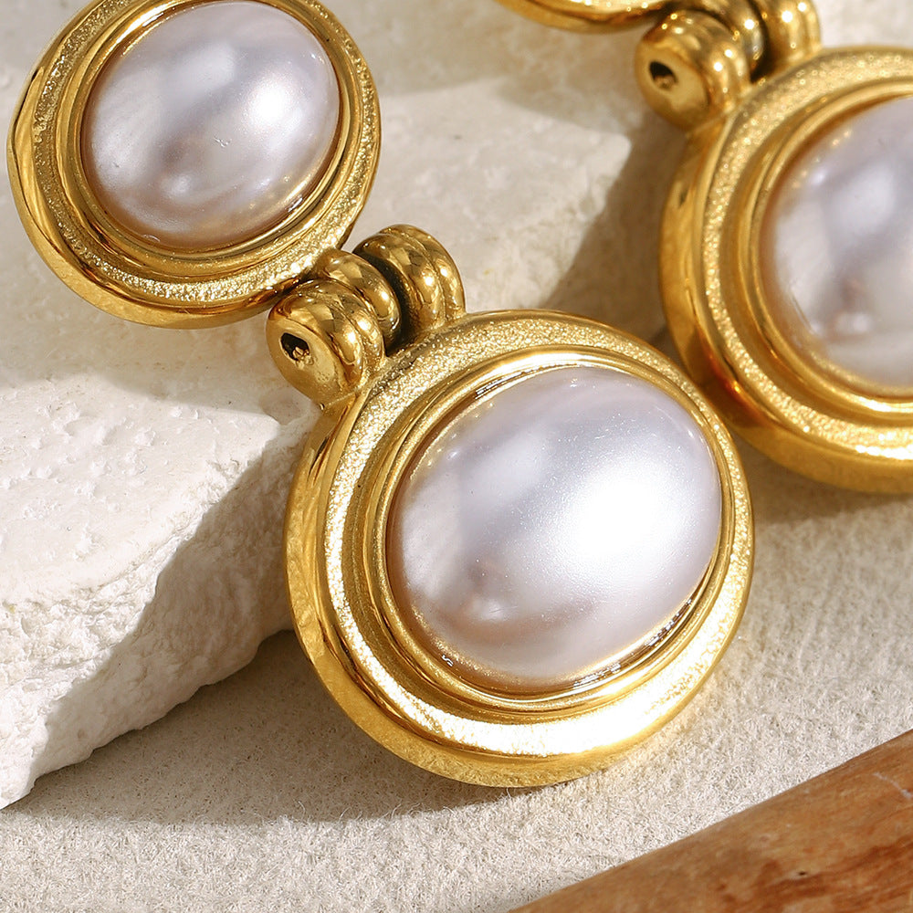 close-up of graduated imitation pearl earrings in rounded metal frames