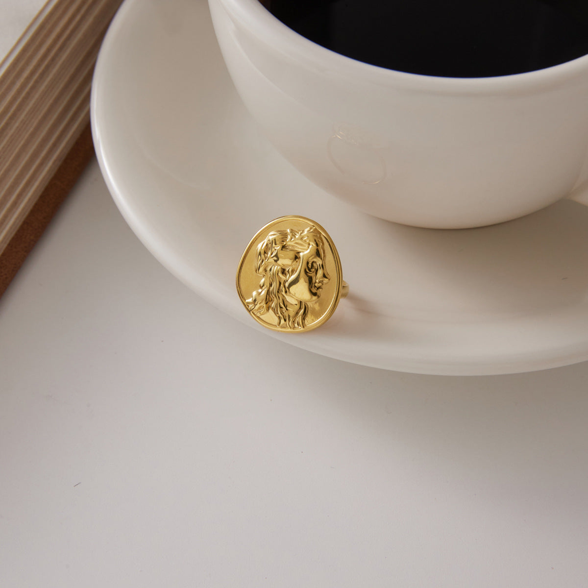Oval portrait ring displayed beside a white cup