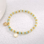 aqua bead seashell charm bracelet arranged on a textured display