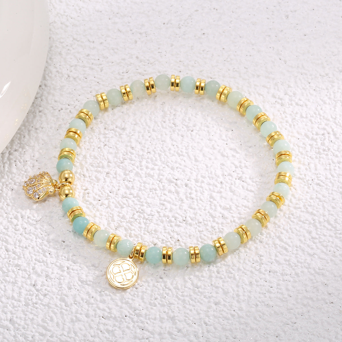 aqua bead seashell charm bracelet arranged on a textured display
