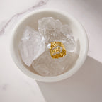 Gold-tone textured ring displayed on pale rocks