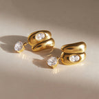 Curved stud earrings and round drops lying on a surface
