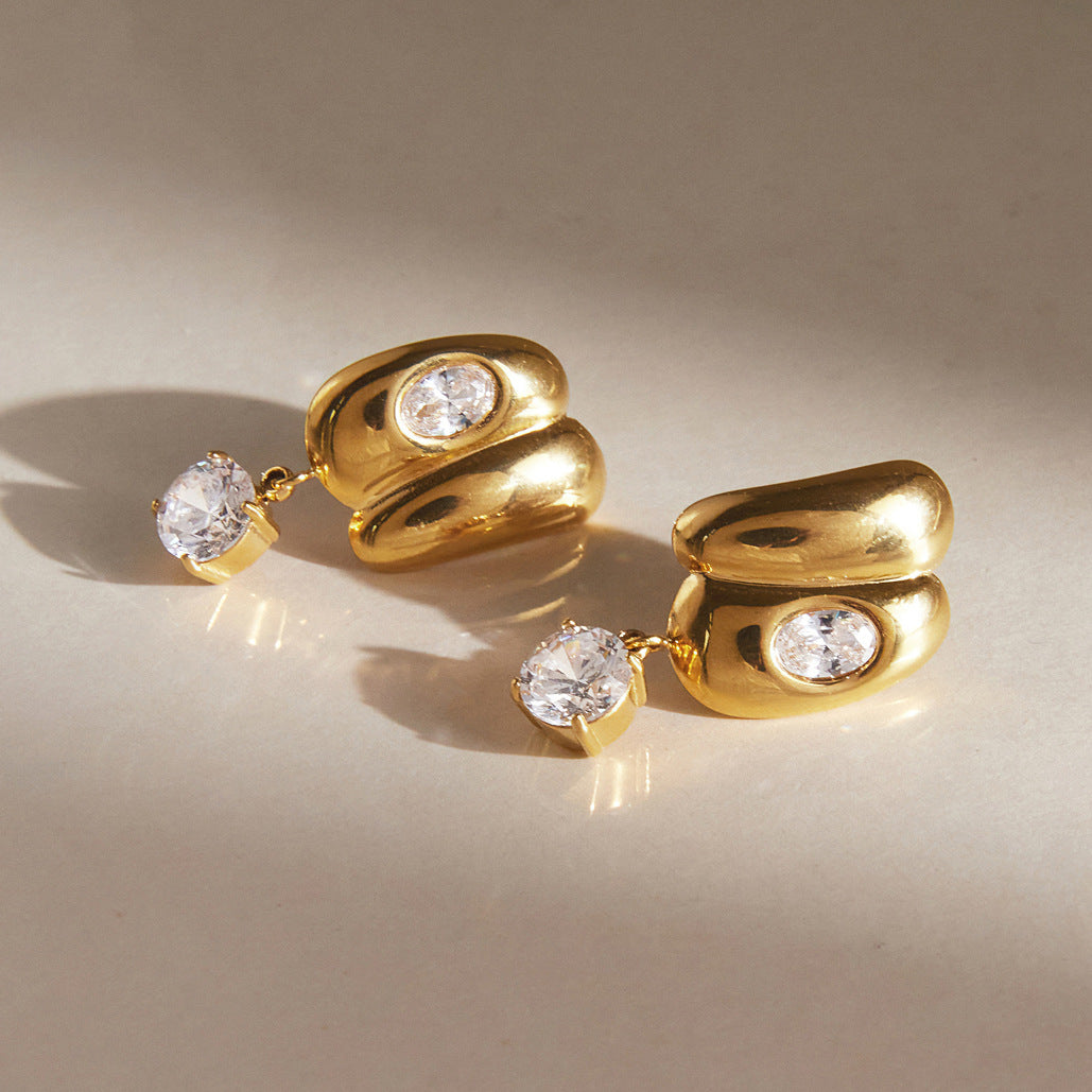 Curved stud earrings and round drops lying on a surface