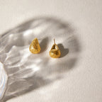 Pair of teardrop studs on pale fabric
