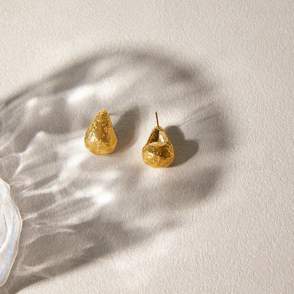 Pair of teardrop studs on pale fabric