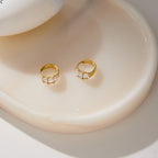 Pair of gold tone stone hoops displayed in a dish