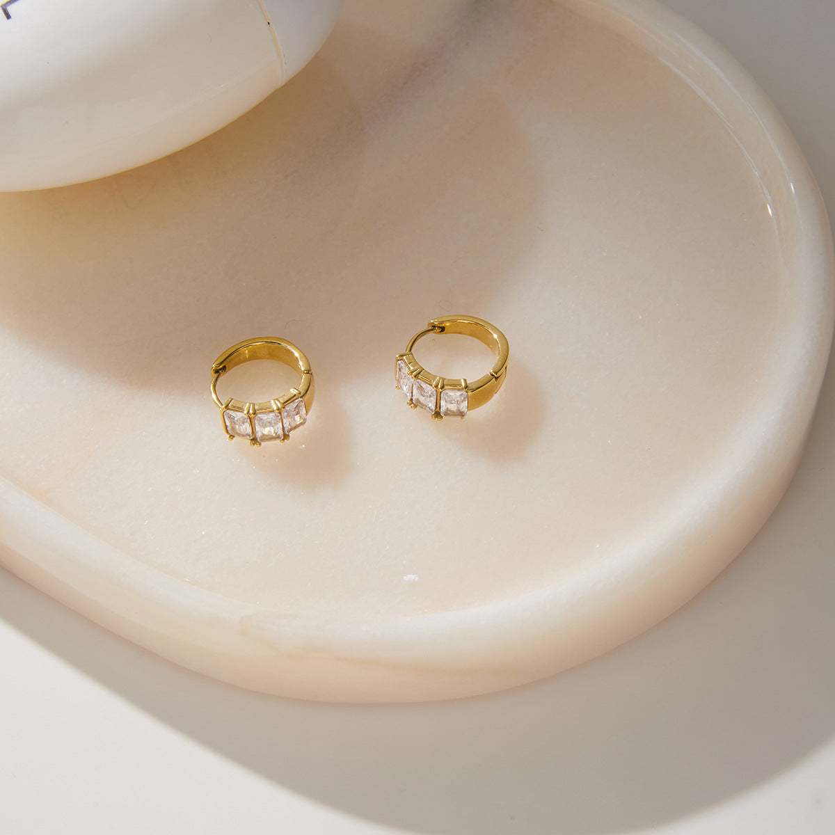 Pair of gold tone stone hoops displayed in a dish