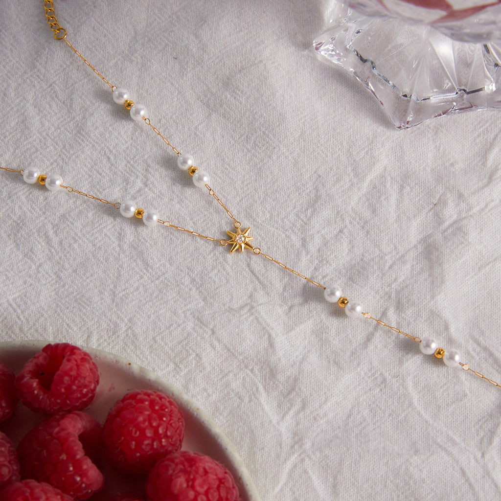 Pearl and starburst hand chain displayed beside raspberries
