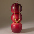 Wave pendant necklace displayed over red apples
