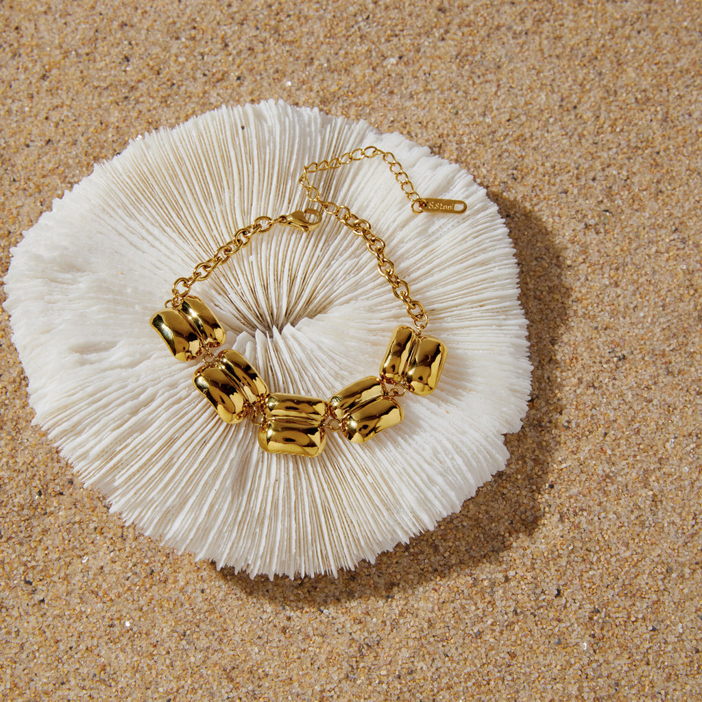 Gold-tone bracelet arranged on a pale shell