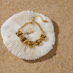 Gold-tone bracelet arranged on a pale shell