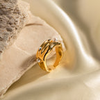 Wavy gold plated ring with white and clear accents on satin