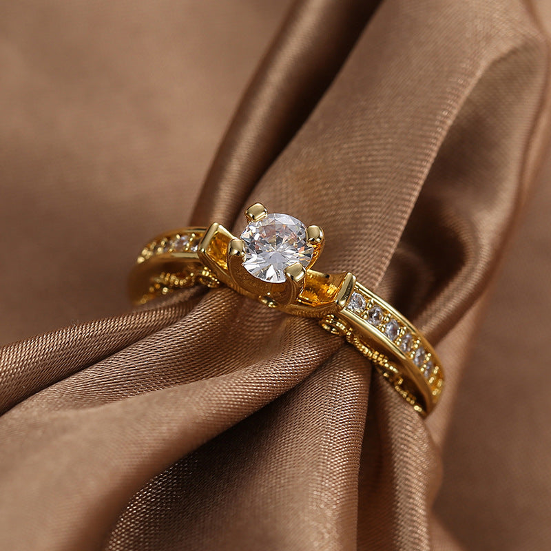 gold plated clear stone solitaire ring styled on brown satin