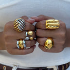 Mixed-metal and gold tone statement rings worn on hands
