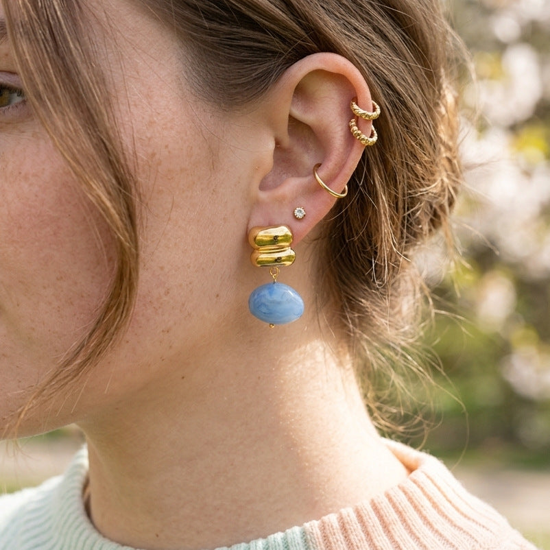 Blue resin drop earring worn on ear