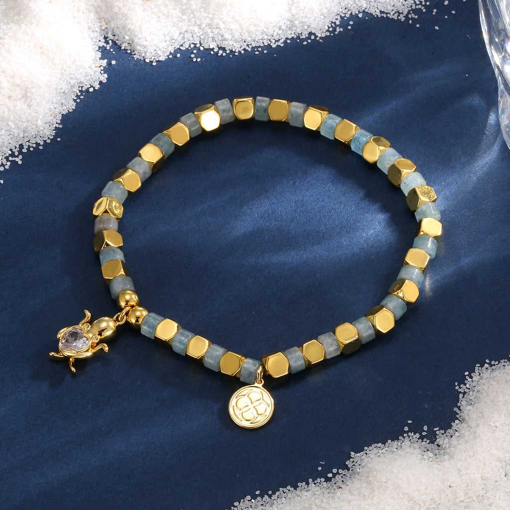 blue-gray bead turtle bracelet styled on navy fabric