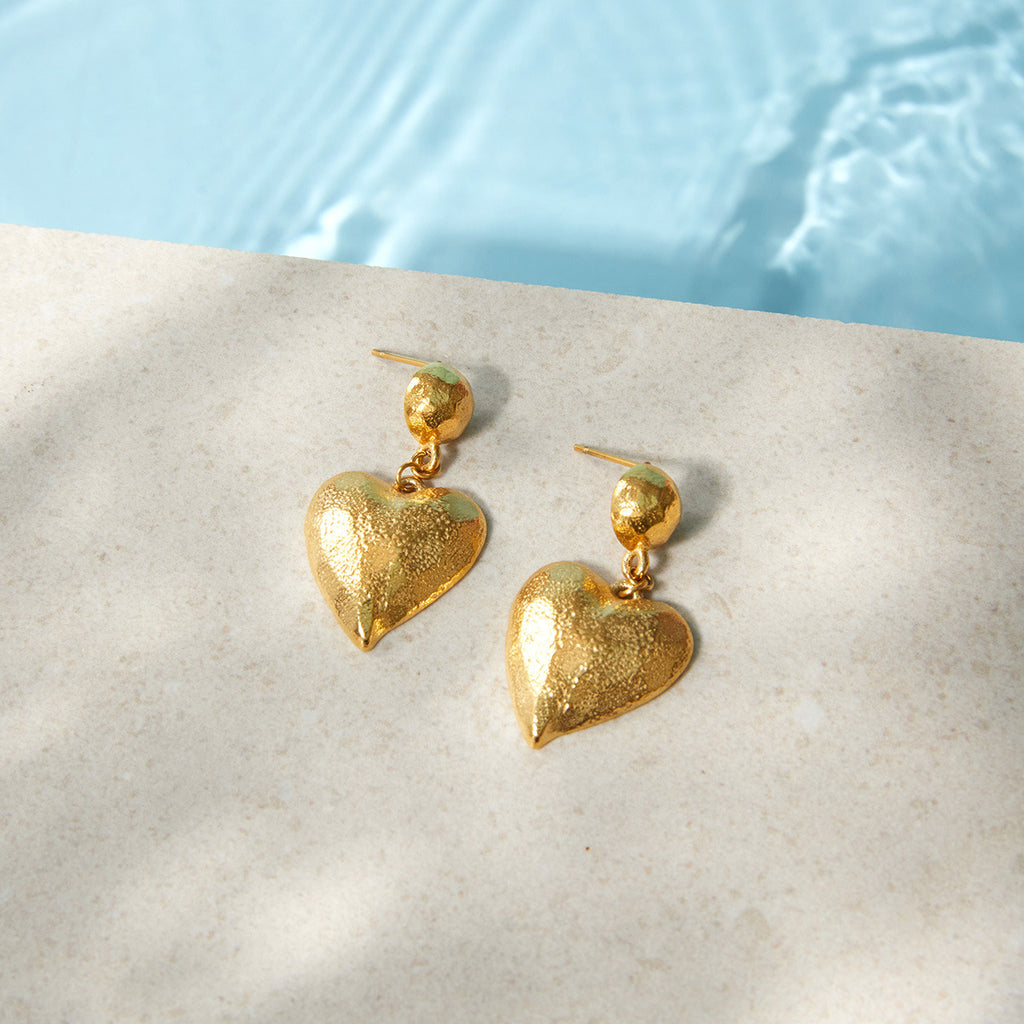 Textured heart earrings beside a pool