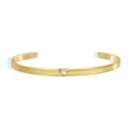 isolated gold plated open cuff with a single heart-shaped setting