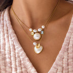 Round white bead necklace layered with a separate heart necklace