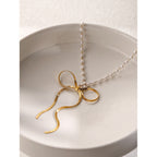 Gold plated bow pendant resting in a white dish
