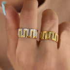 Gold tone and two-tone meander rings worn on fingers