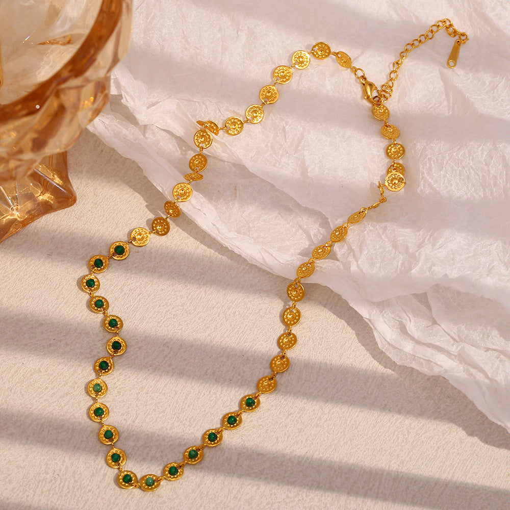 gold plated green stone link necklace arranged on a book