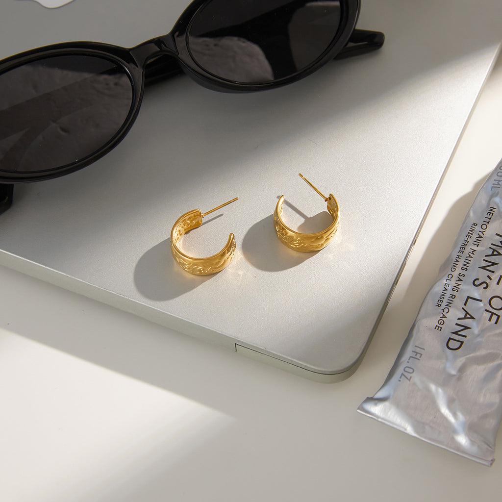 pair of floral relief gold plated hoops in a styled setting