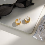 pair of floral relief gold plated hoops in a styled setting