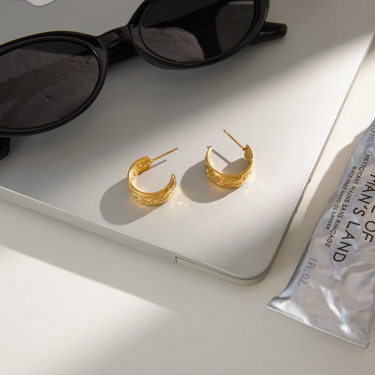 pair of floral relief gold plated hoops in a styled setting