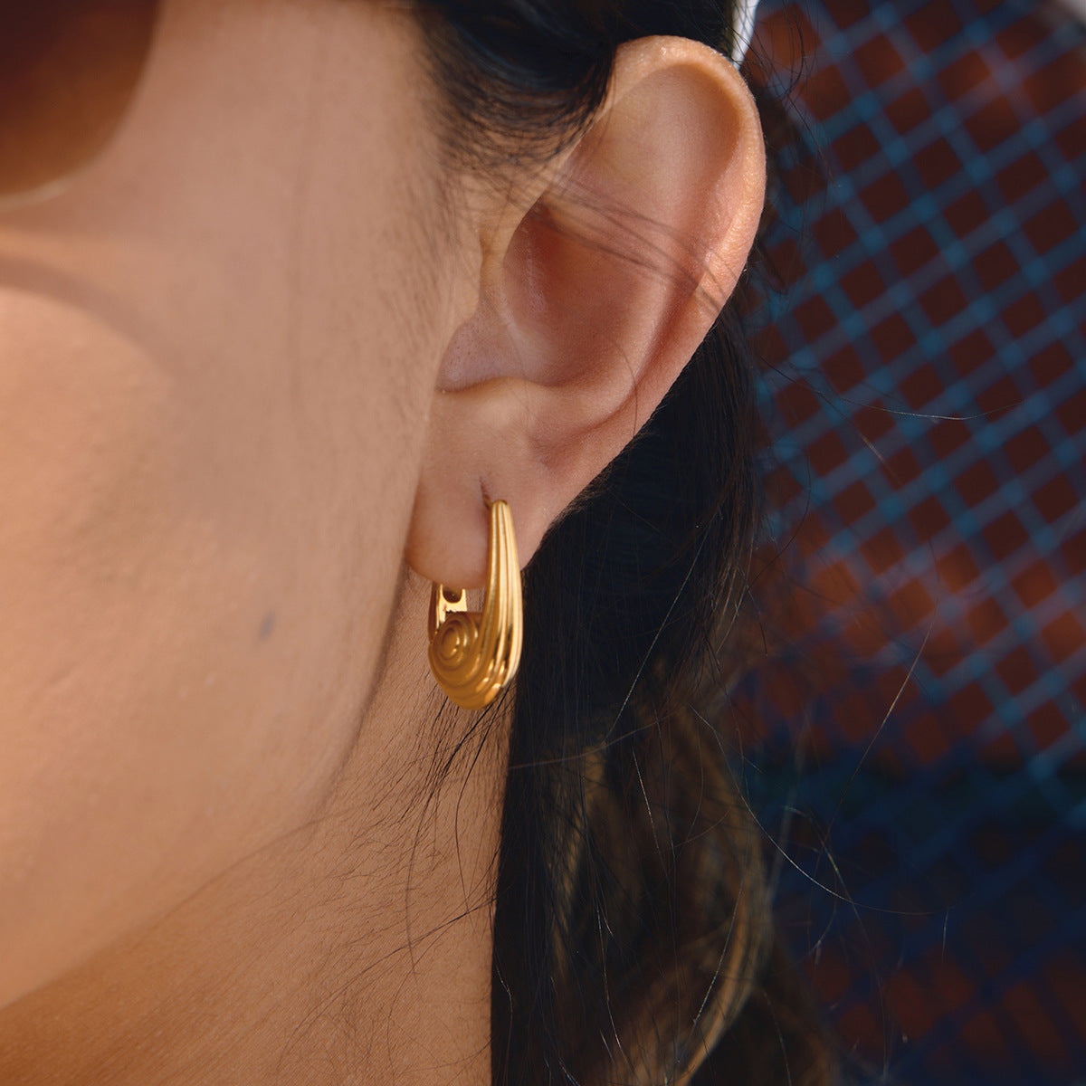 side view of sculptural clear-rhinestone huggie earring