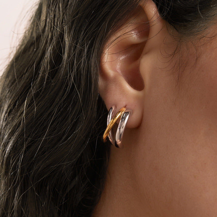 Two tone triple-curve earring worn close-up