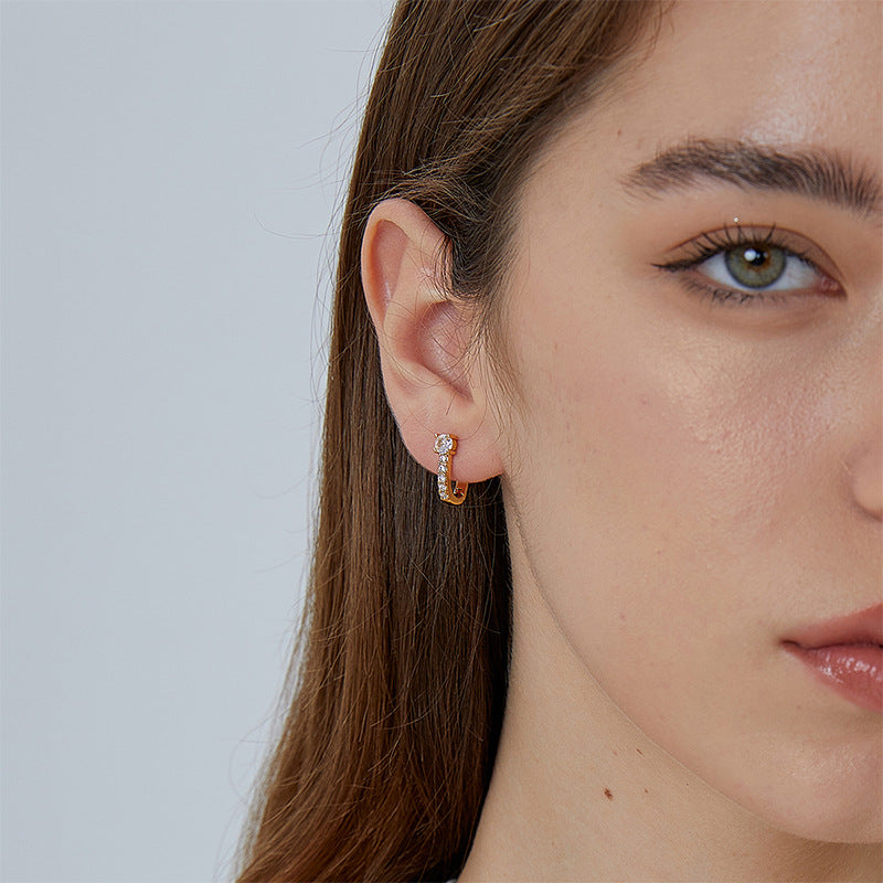slim graduated zirconia huggie earring worn on the ear