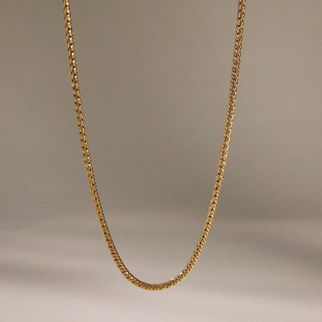 Plain gold tone stainless steel chain hanging in a shallow curve