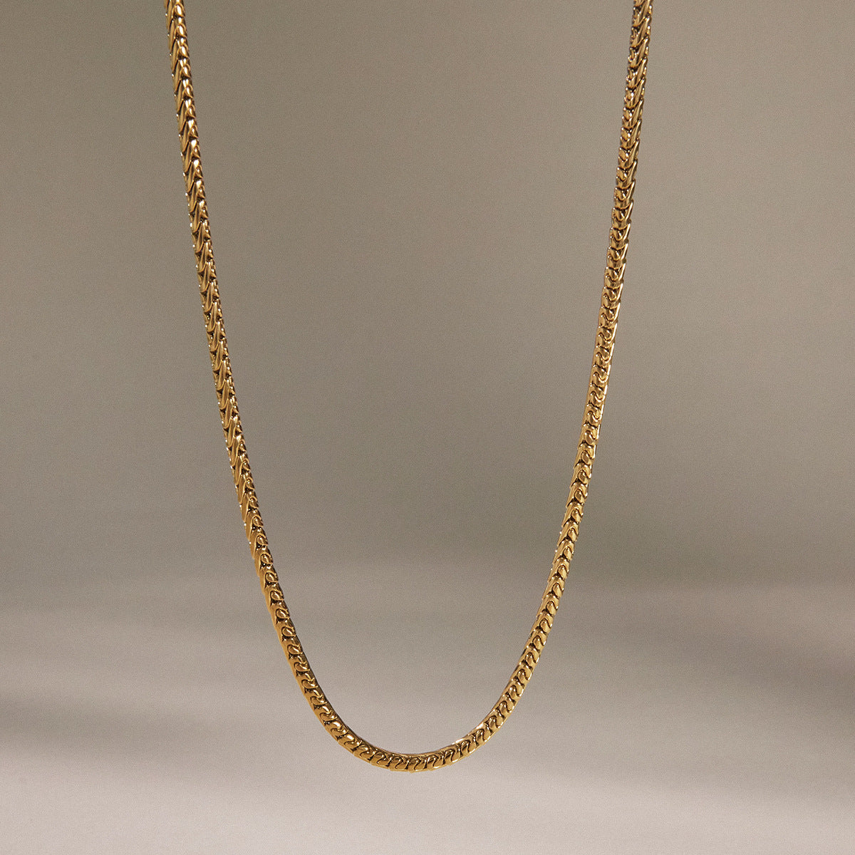 Plain gold tone stainless steel chain hanging in a shallow curve