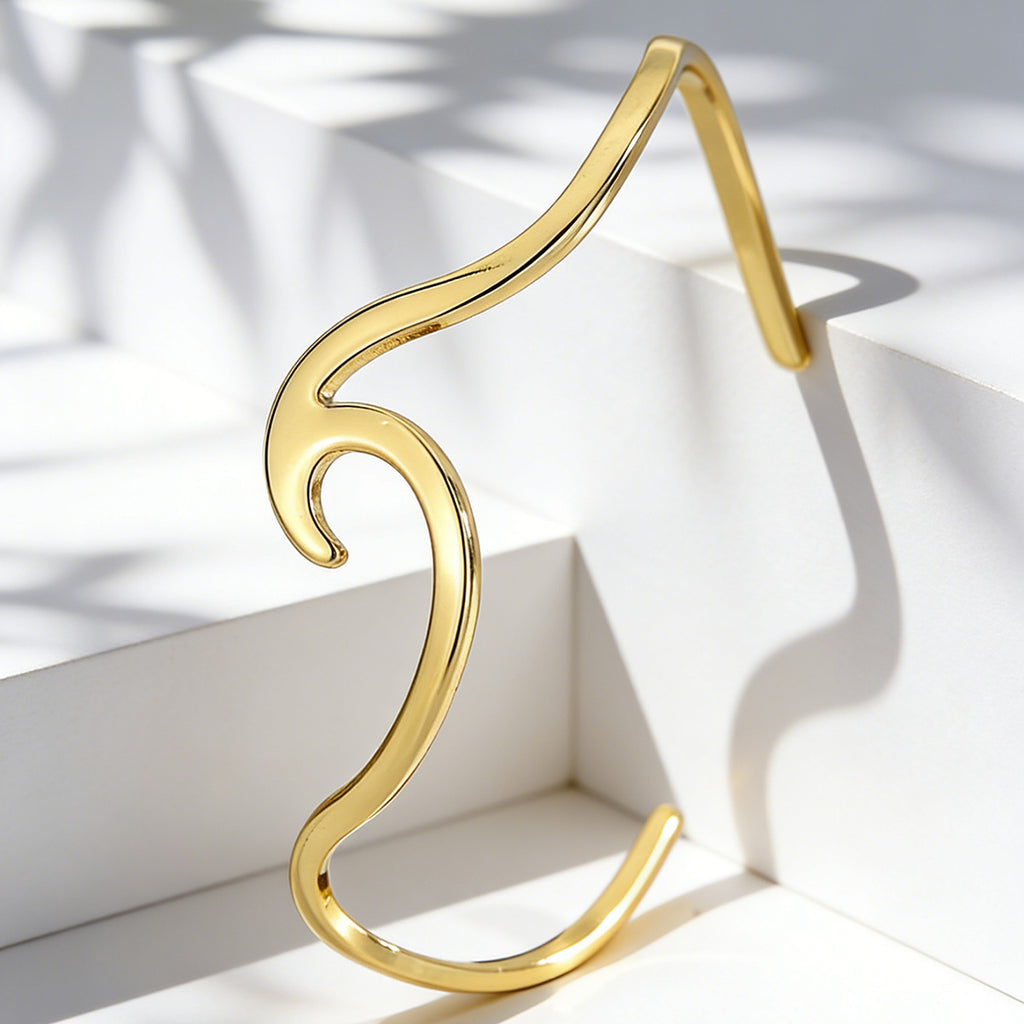 gold plated sculptural wave cuff shown in angled studio light