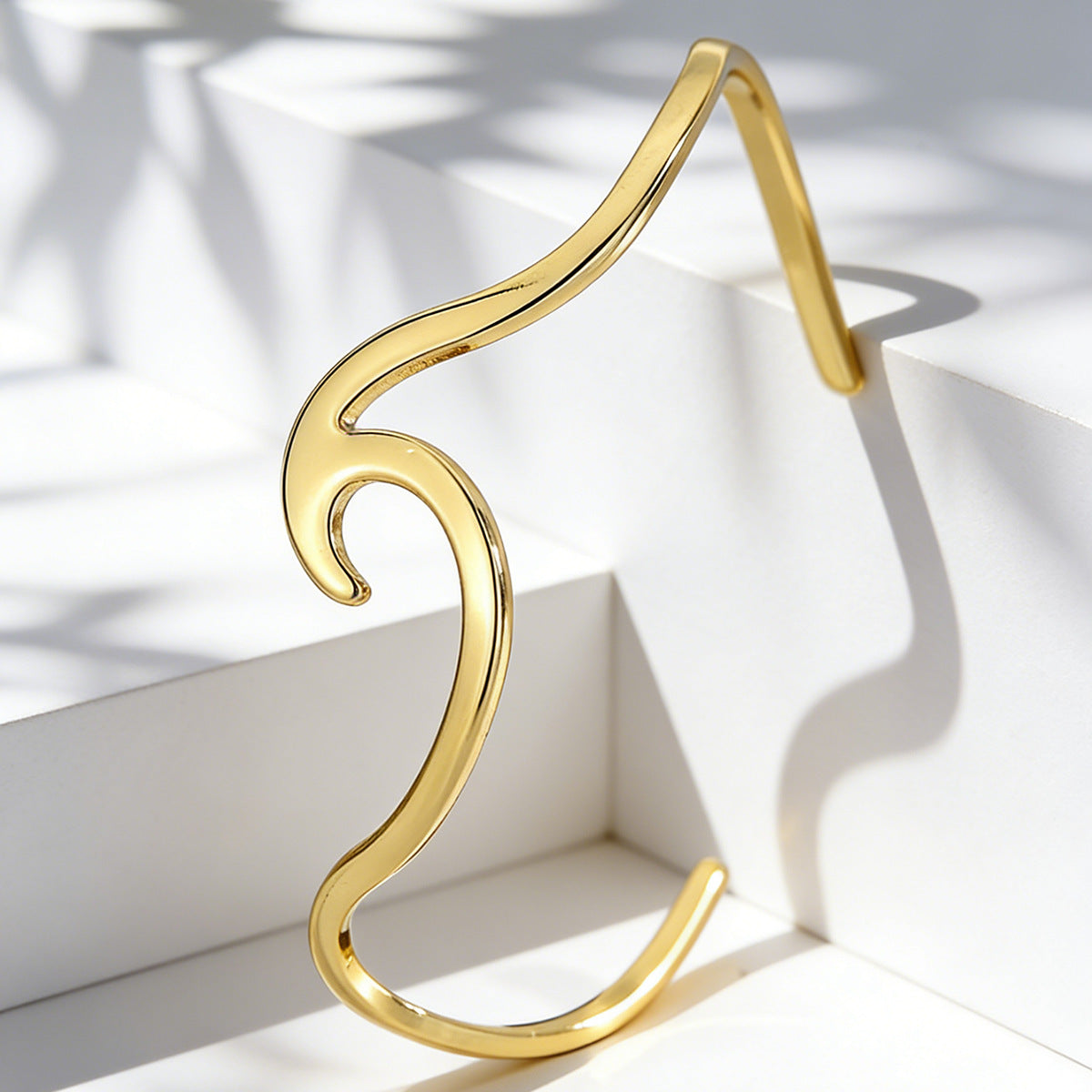 gold plated sculptural wave cuff shown in angled studio light