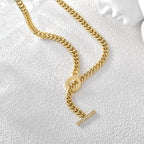 Cuban-link necklace and stone-set toggle bar on a textured surface