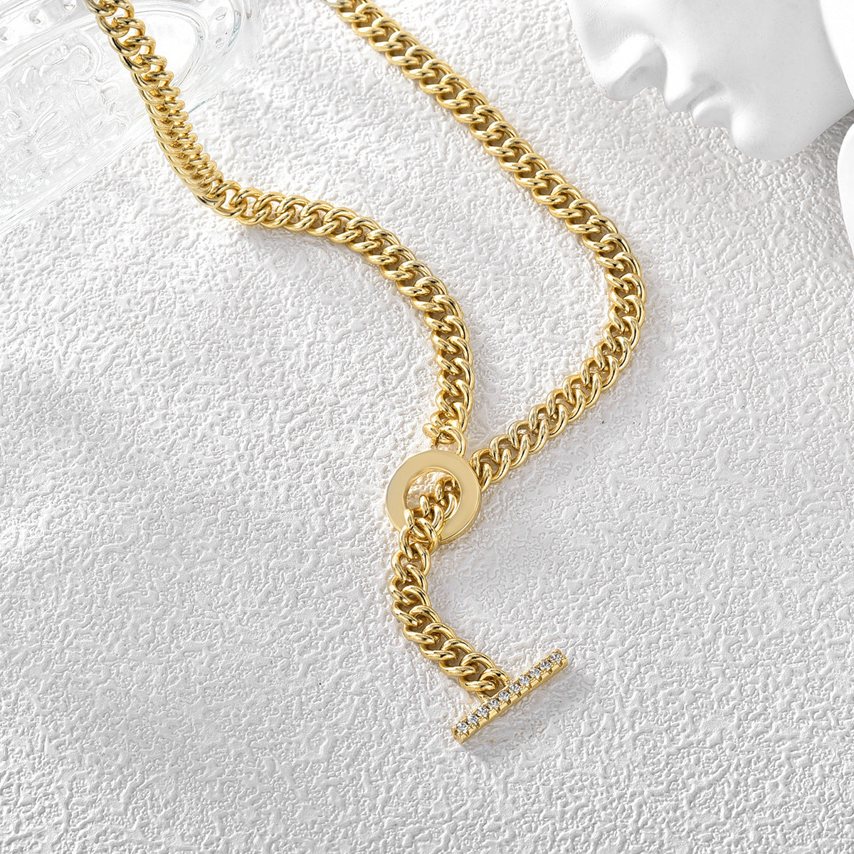 Cuban-link necklace and stone-set toggle bar on a textured surface