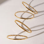 Clear accent stainless steel bangle collection arranged on a light surface