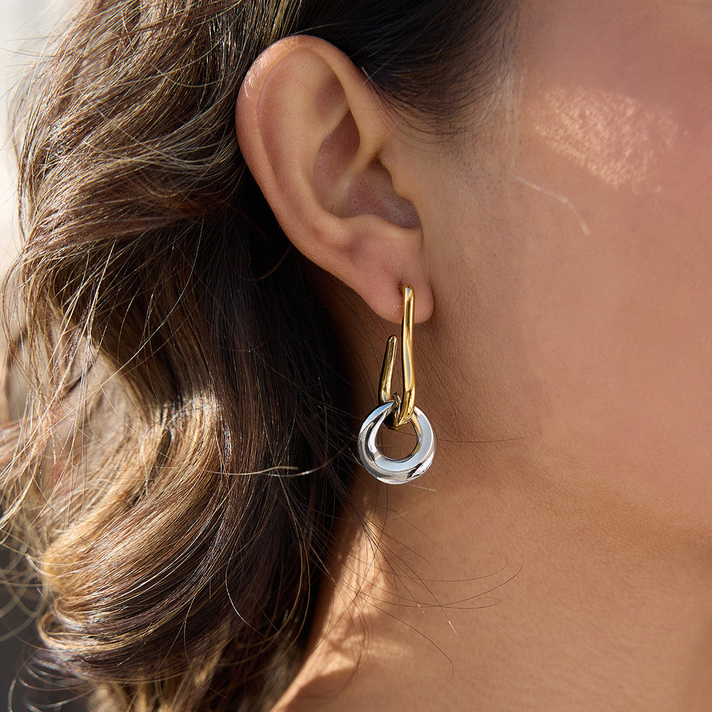 two-tone interlocking stainless steel drop earrings worn on ear